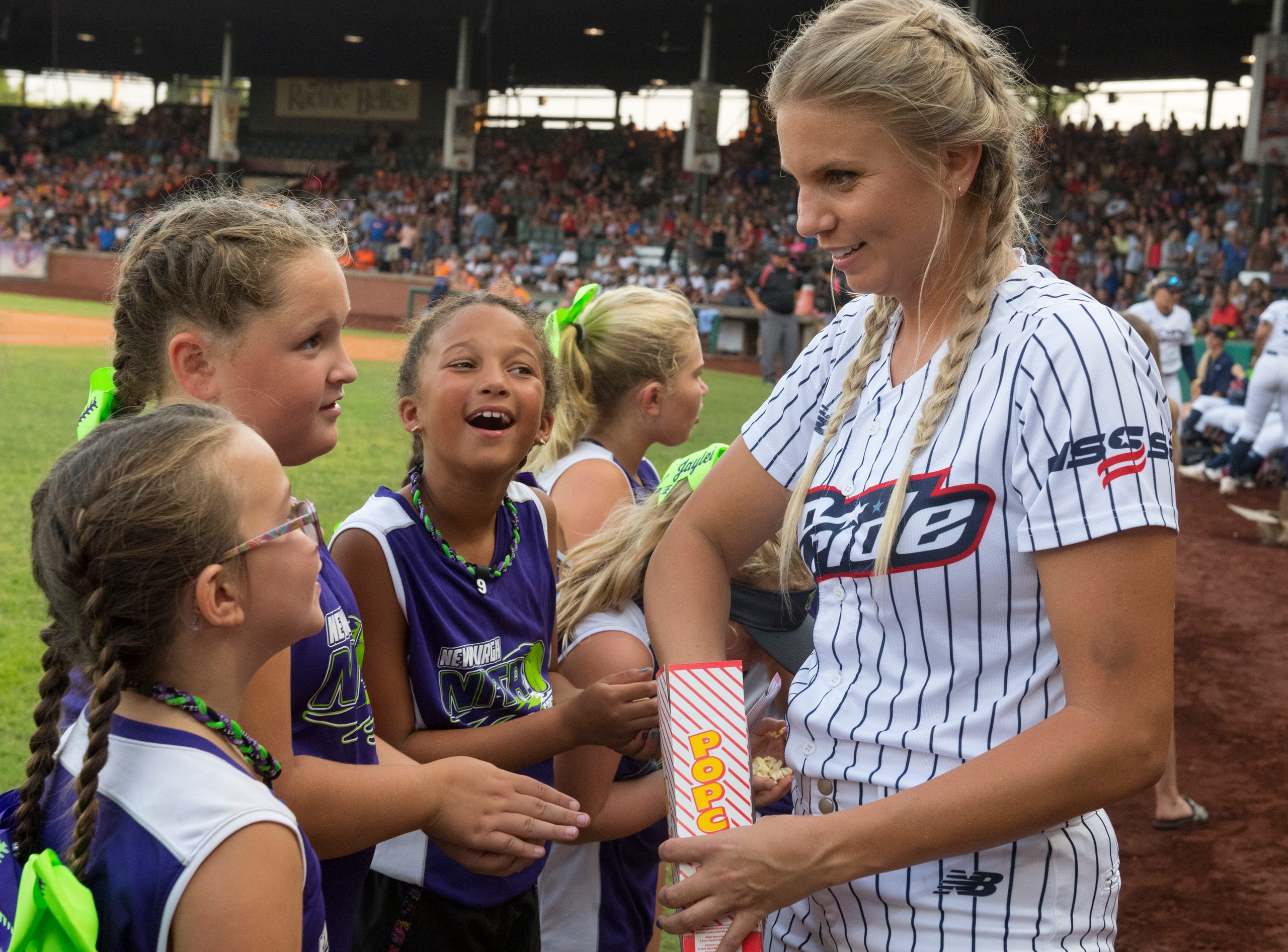 USSSA Pride’s Jessica Burroughs (16) hands out popcorn to the Newburgh Nitro softball team ahead of the exhibition game between USSSA Pride and Team Florida at Bosse Field in Evansville, Ind., Wednesday evening, July 14, 2021.