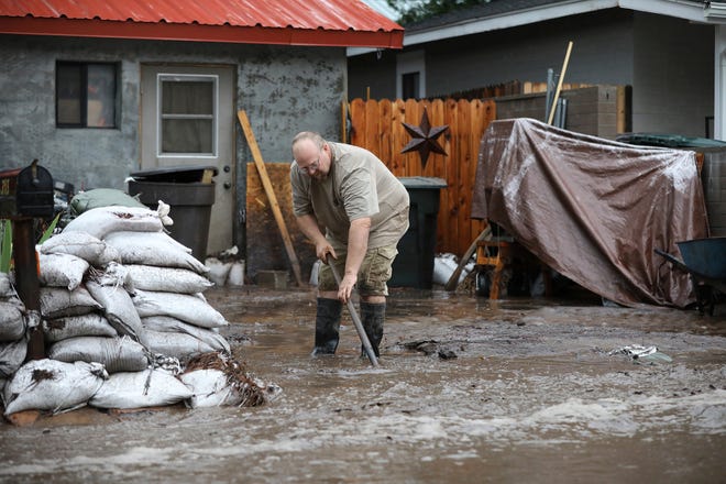 A resident shovels back floodwater as monsoon rains fell on the Museum Fire burn area causing flooding from the Paradise Wash in east Flagstaff on July 14, 2021.
