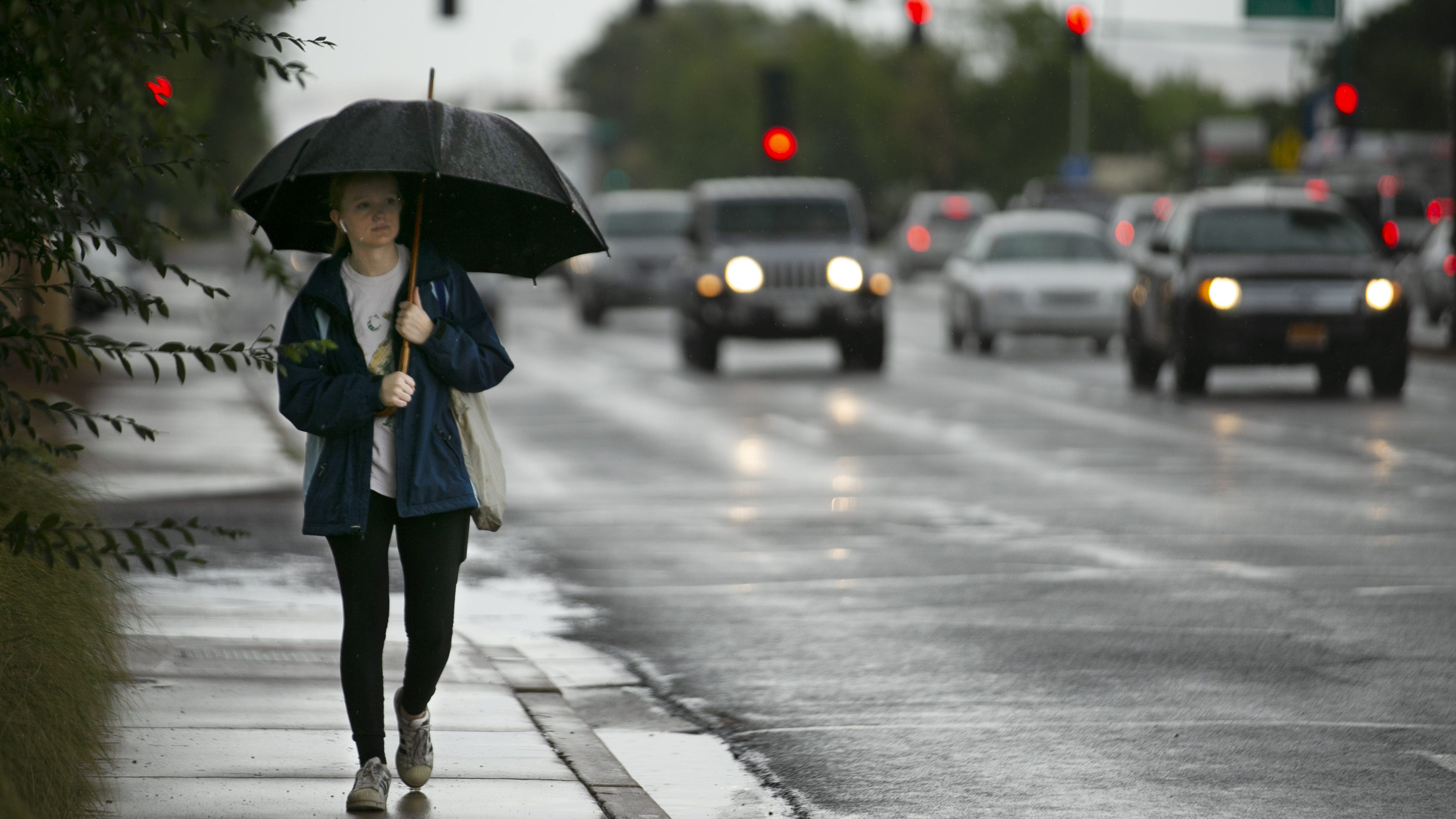 Lauren Matz, 15, attempts to stay dry under an umbrella while walking home from the store in Phoenix on July 16, 2021.