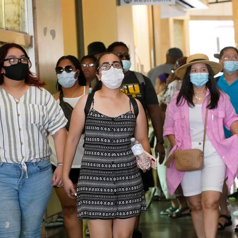 Visitors wear masks as they walk in a shopping dis
