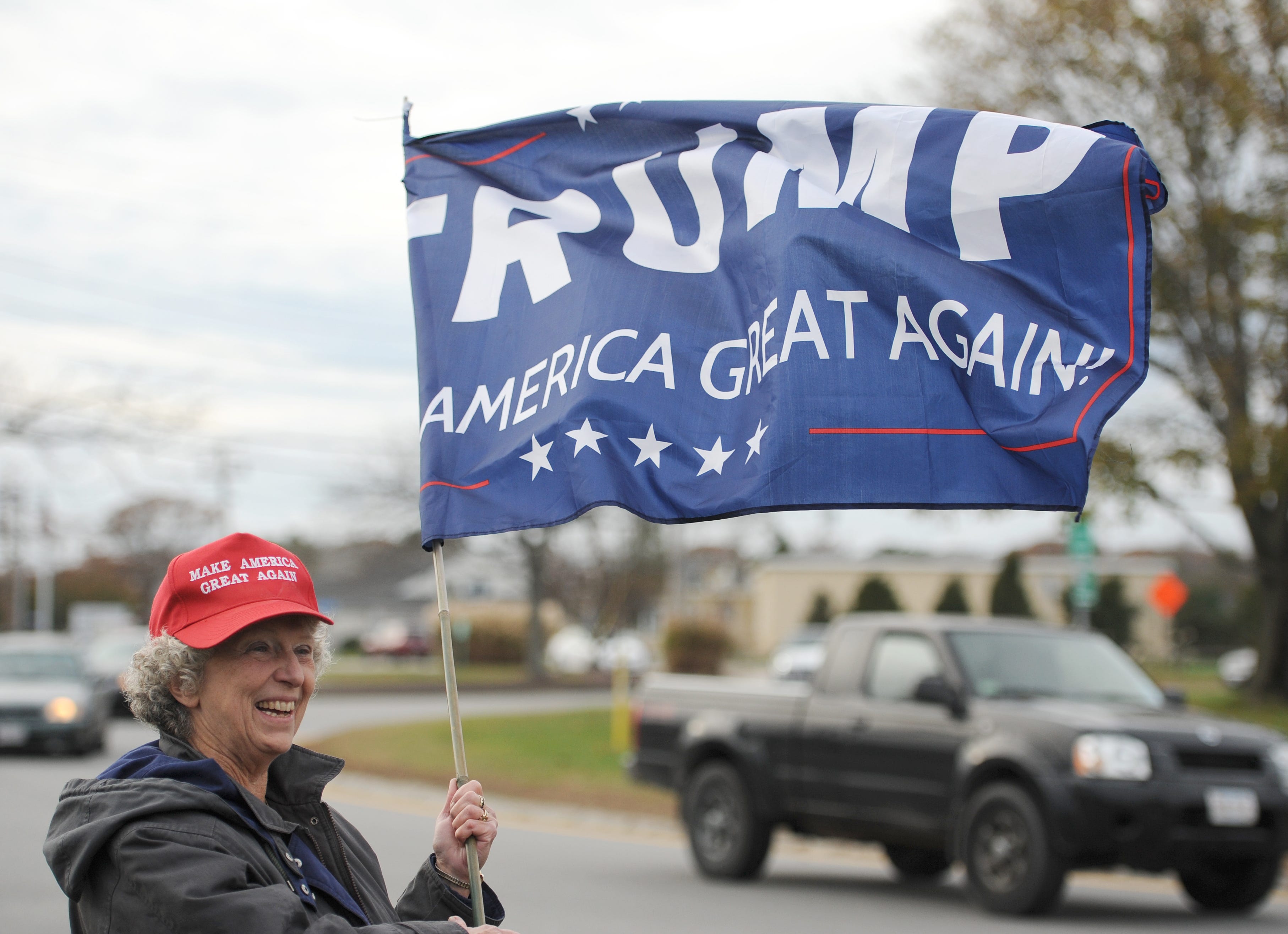 Linda Zuern, of Bourne, waves a Trump flag during a rally at the airport rotary in Hyannis on Nov. 7, 2019. Zuern and others gathered in support of President Donald Trump.