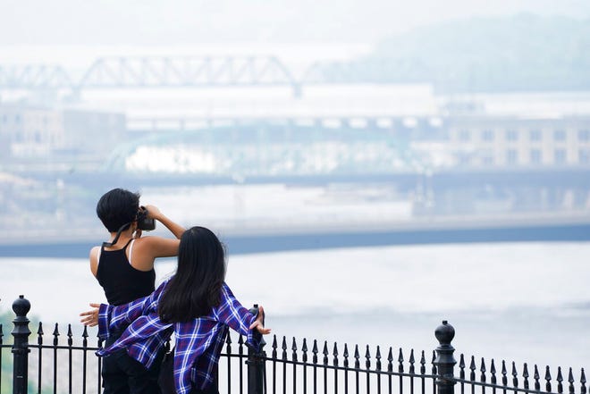 People visit Parliament Hill in Ottawa on Monday, July 19, 2021. Smoke from forest fires hangs over the city and the Ottawa River, and it will cause a Code Orange Air Quality Action Day across most of Pennsylvania on Tuesday.  (Sean Kilpatrick/The Canadian Press via AP)