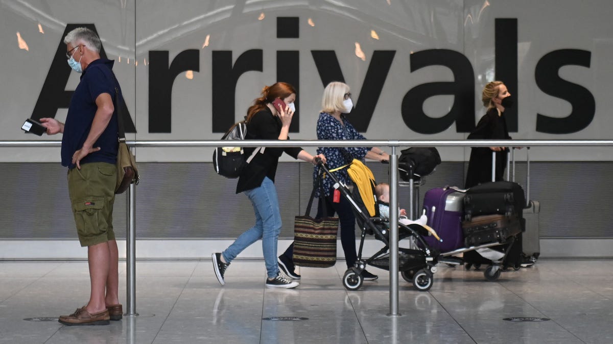 In this file photo taken on June 3, 2021, passengers push their luggage on arrival in Terminal 5 at Heathrow airport in London.