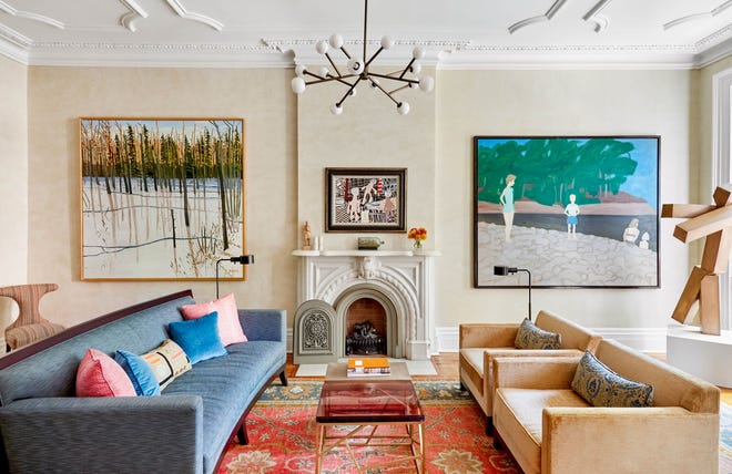 For this circa 1900 West Village townhome in New York, interior designer Kathleen Walsh designed the living room around a vibrant area rug. The bluish-green upholstered sofa and apricot-taupe chairs draw from secondary colors in the rug. The wall art also relates to the blues and tans in the rug.