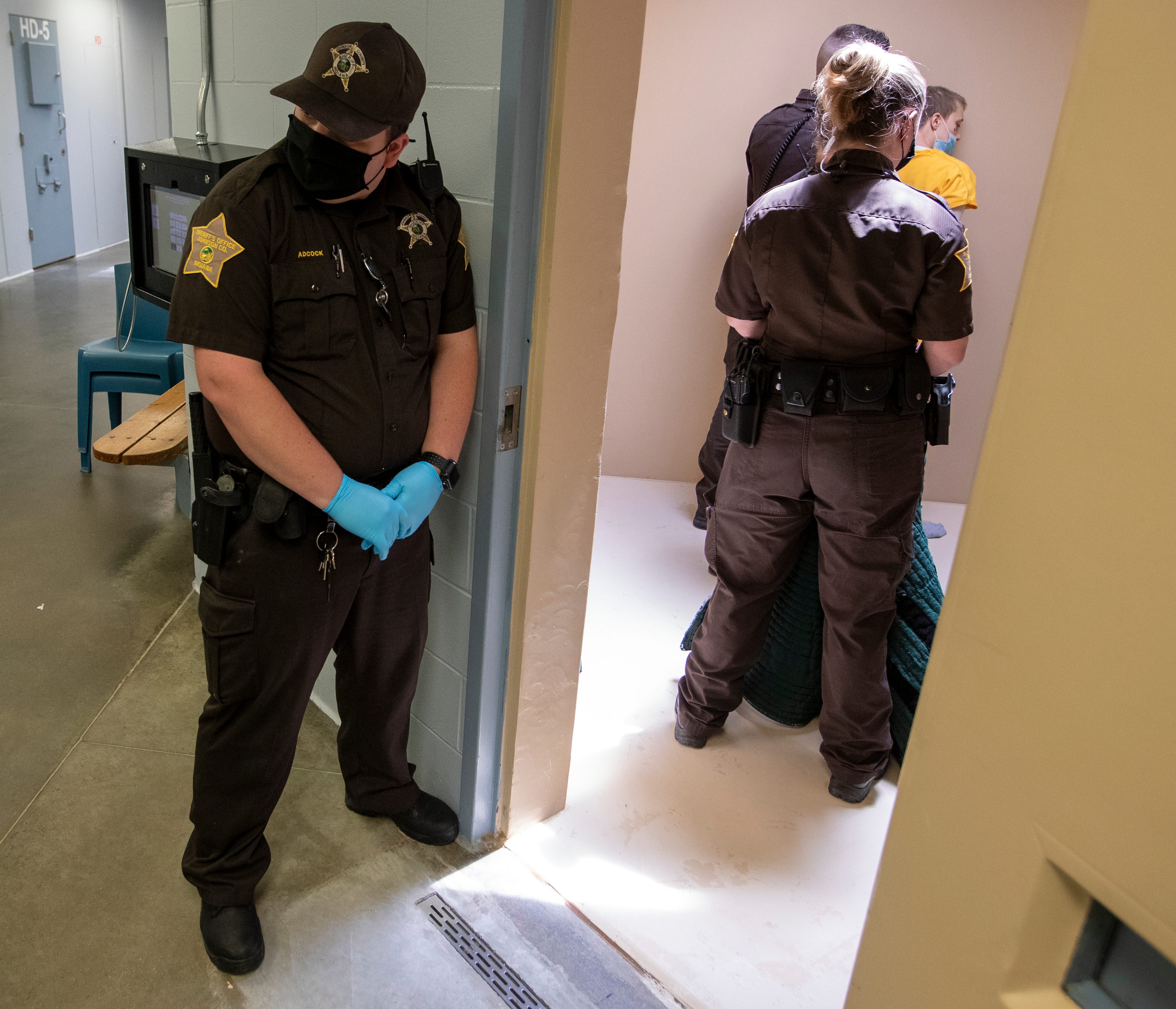 Corrections officers work to place a green suit made of rip-resistant fabric on a detainee who is being put in a padded cell Thursday, June 17, 2021, at the Johnson County Jail in Franklin, Ind. This type of action is standard policy at facilities like the Johnson County Jail, which has specially padded rooms like this one to protect inmates who are deemed a danger to themselves. Not all county-run jails in Indiana have enough of these rooms for people on suicide watch.