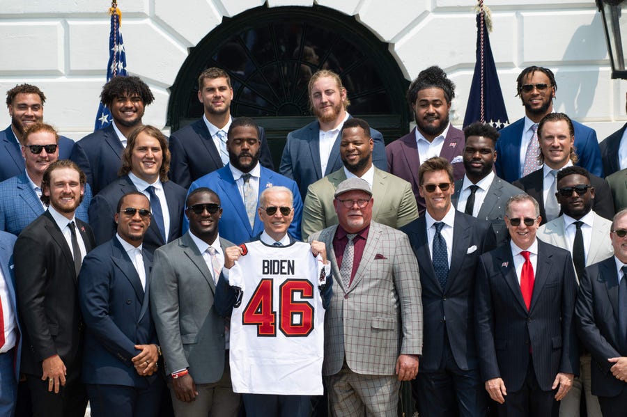 US President Joe Biden holds a jersey alongside Tampa Bay Buccaneers head coach Bruce Arians (C) and quarterback Tom Brady (2nd R) during a ceremony honoring the Tampa Bay Buccaneers NFL football team for their Super Bowl LV Championship on the South Lawn of the White House in Washington, DC, July 20, 2021. (Photo by SAUL LOEB / AFP)