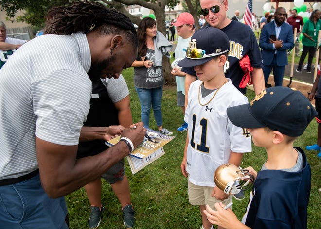 New York Jets running back and Central Bucks South alum Josh Adams, left, signs autographs for John Logan, 13, center, of Collegeville, and his brother, Brendan Logan, 9, following a groundbreaking ceremony at DocterAdams Community Park in Warrington on Wednesday.