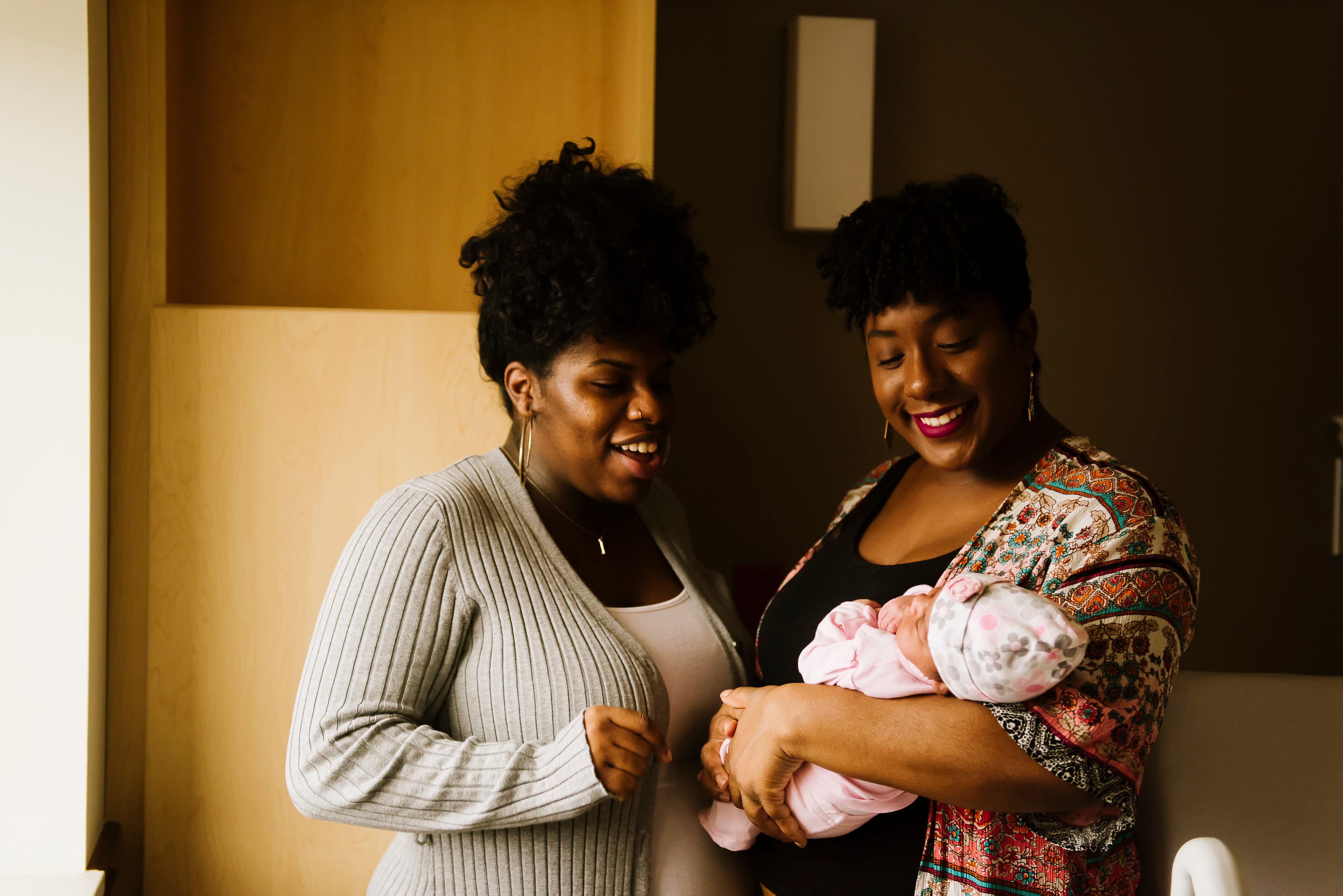 Sequoia Kemp, a certified doula, stands next to her sister and client while holding her new niece in the hospital.
