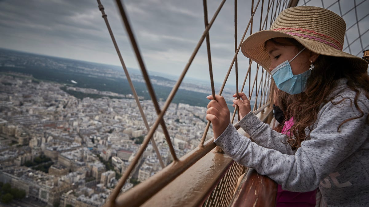 A girl looks down at Paris from the top of the Eiffel Tower as the iconic landmark reopened for the first time in over 8 months on July 16, 2021.