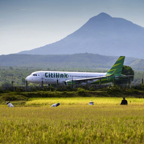 A Citilink airplane takes off from a runway beside