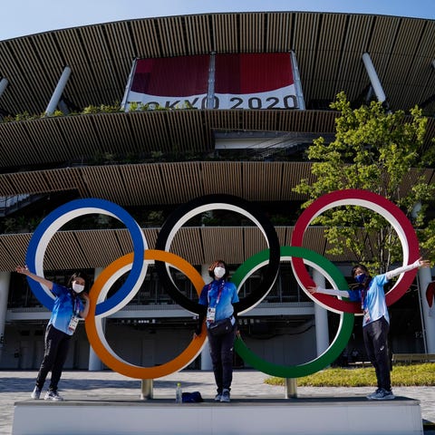 Volunteers pose with the Olympic rings during the 