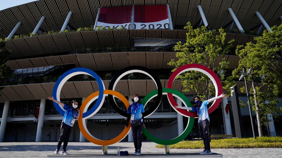 Volunteers pose with the Olympic rings during the opening ceremony for the Tokyo 2020 Olympic Summer Games at Olympic Stadium.
