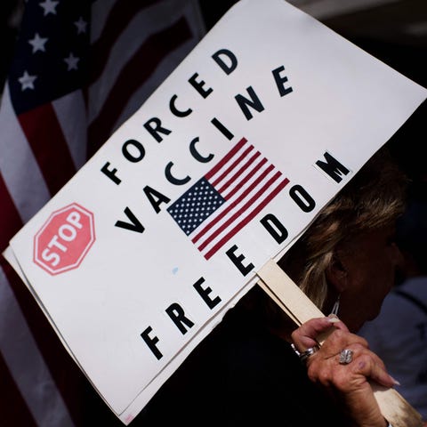 Anti-vaccine rally protesters hold signs outside o