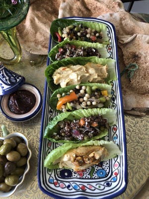 Individual romaine leaves filled with Israeli couscous (onions, edamame, red, orange and green peppers), quinoa salad with roasted walnuts, currants, peas celery, and shredded coconut and traditional hummus.