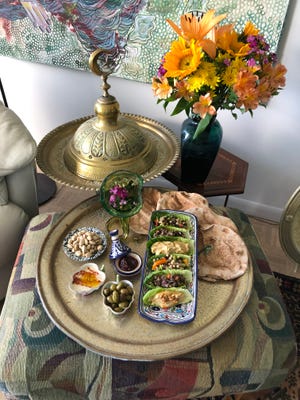 Clockwise in the mezza platter: Whole wheat pita bread, salads in romaine leaves, green olives, tahini, Tunisian harissa and pistachio nuts.