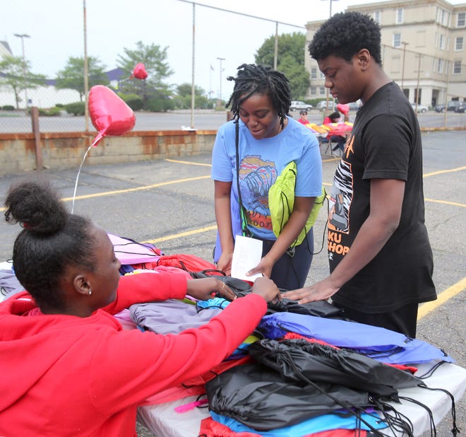 India Thomas, center, helps her son Curtis Pratt Jr. selecting his school backpack at Abundance of God Christian Church in Canton on Saturday, July 24, 2021. Assisting them is Jermyra Patterson, left. The event was sponsored by the CommunityUNITY Organization.