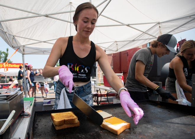 Lizzie McClain, an employee at BIGS Meat Wagon, cooks sandwiches on the grill at their booth at Taste of Fort Collins on July 25, 2021. Coloradoan file photo