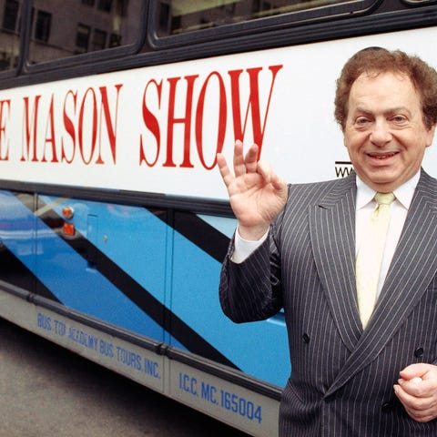 Actor and comedian Jackie Mason stands beside a bu