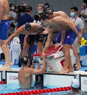 Zach Apple is congratulated by teammates after anchoring the USA to a gold medal in the men's 4x100m freestyle relay final at Tokyo Aquatics Centre.