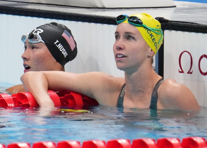 Torri Huske (USA) y Emma McKeon (AUS) miran los resultados en la final femenina de 100m mariposa.