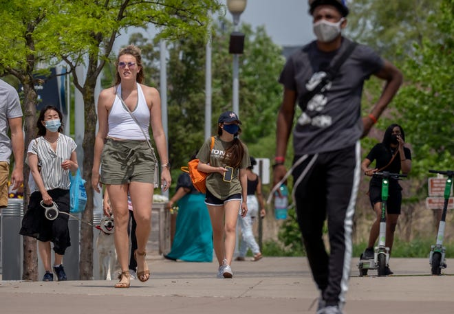 2021年5月21日金曜日のデトロイトの暑い日にデトロイトリバーウォークを訪れている間は、マスクを着用する人もいれば、マスクを着用しない人もいます。