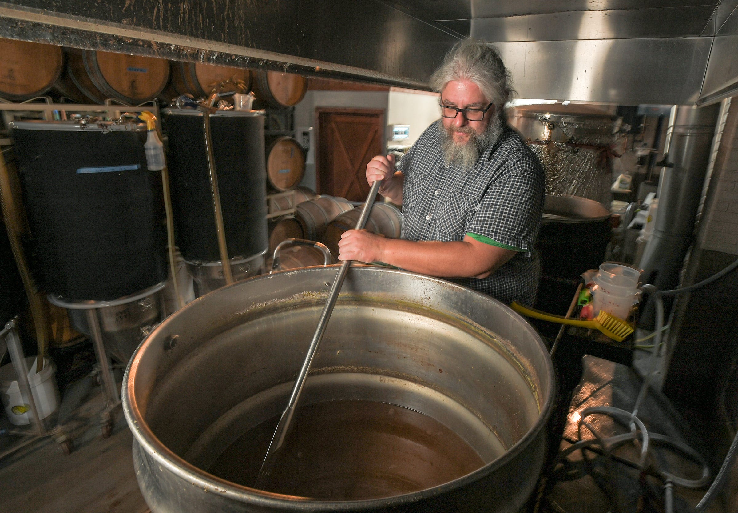 Keston Helfrich, Head of Brewing Operations Carolina Bauernhaus Brewery & Winery, checks a batch in Anderson, S.C. Tuesday, July 27, 2021. The company also has a location in Greenville. 