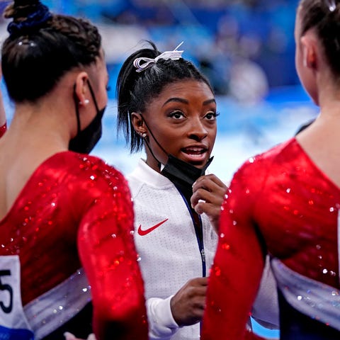 Simone Biles (USA) talks with her team after pulli