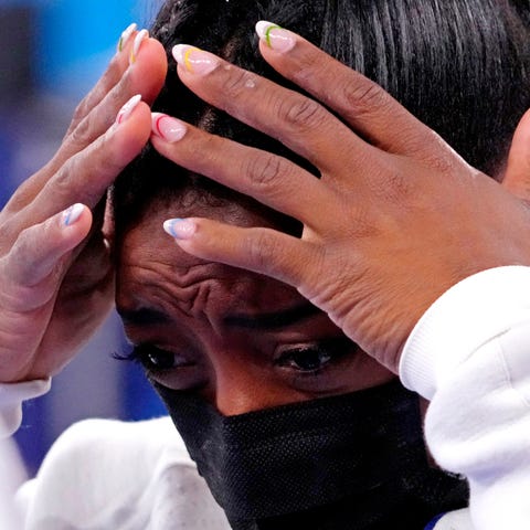 Simone Biles reacts after pulling out of the women