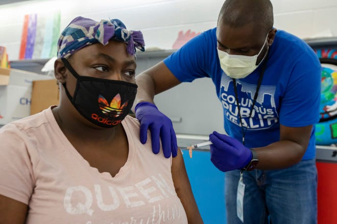 Tynesha Murphy receives her COVID-19 vaccination shot from licensed practical nurse Akintoye Ogundola at Sullivant Gardens Community Center in Columbus, Ohio July 15, 2021. "I've got a daughter and I want to go back to school," Murphy said about getting her vaccine. "A lot of places are requiring a vaccine now."