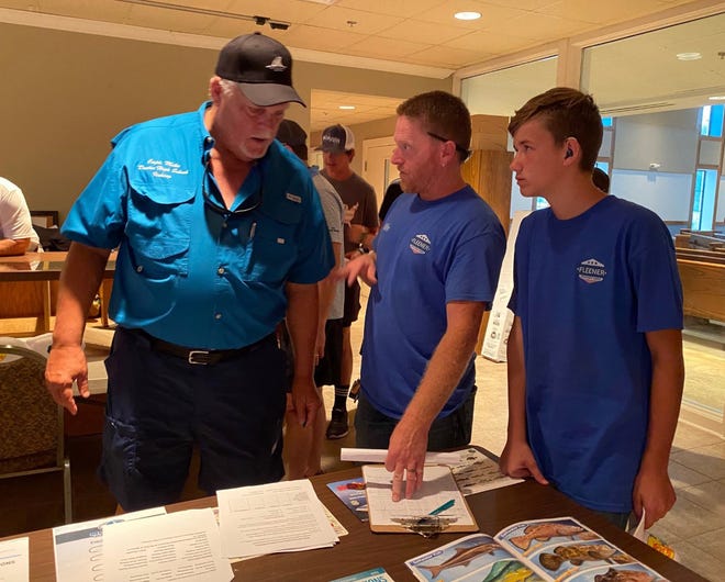 Capt. Mike Parker, left, who will be teaching the fishing class at Destin High School, talks with a couple of students following Tuesday night's meeting. About 60 people attended the meeting to learn about the curriculum for the class.