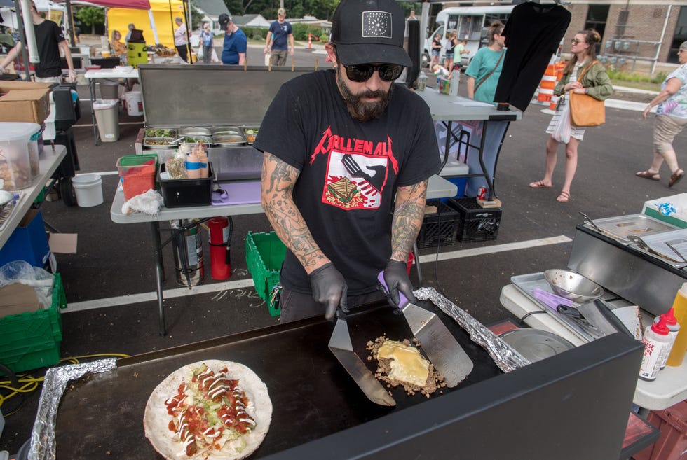 Grill 'Em All food stand owner Stephen LeMasters whips up one of his specialty menu items, a bodega chopped cheese wrap, during his weekly Wednesday evening appearance at the Keller Station Farmers Market in Peoria.