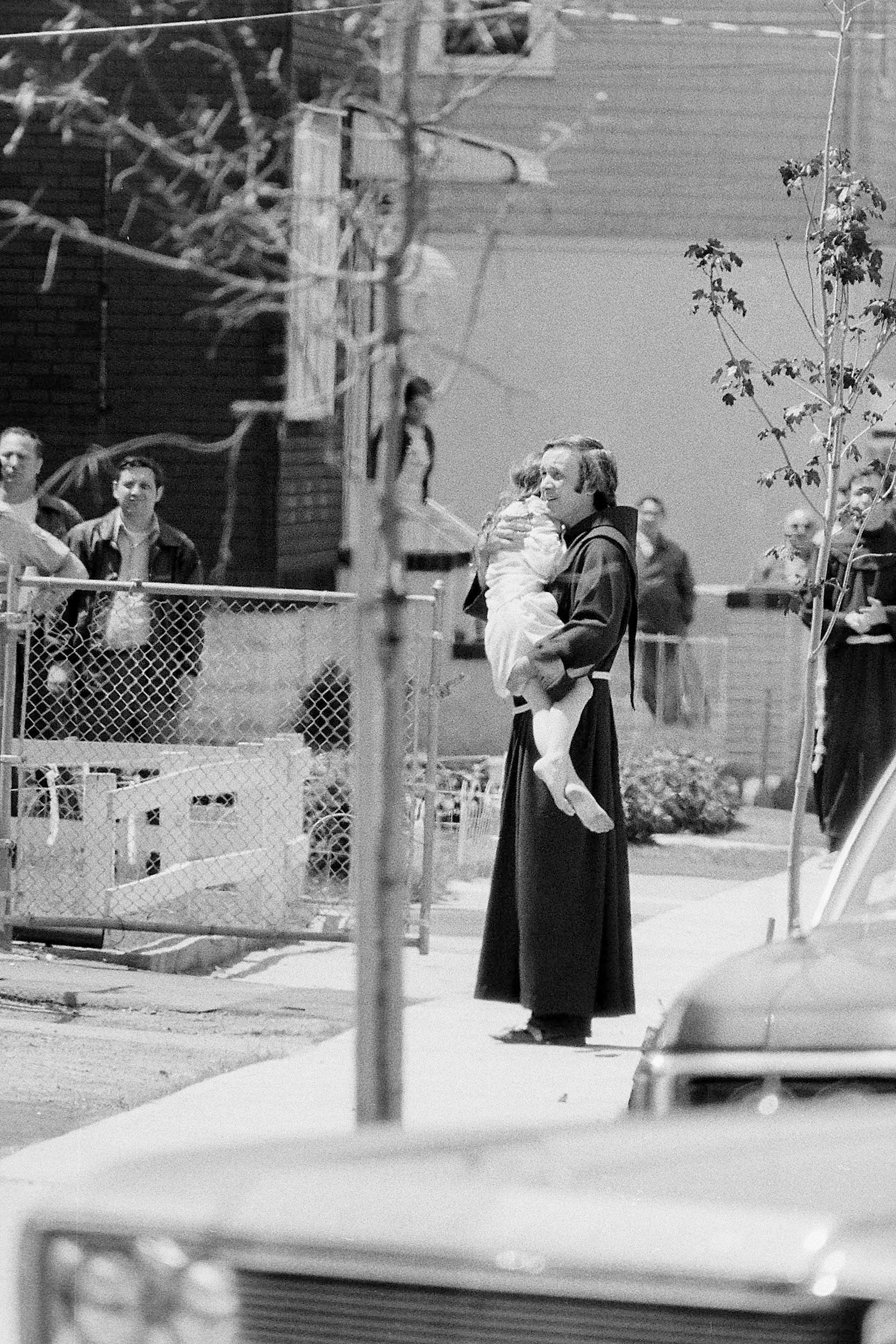 Father Mychal Judge comforts one of the Hyams children during a police standoff with James G. Hyams who was holding his wife and their three children hostage in his wife's home with a shotgun and two handguns in Carlstadt, N.J., on May 19, 1974. During the all-day seige, Hyams ahd fired three shots and police fired one. No one was injured.