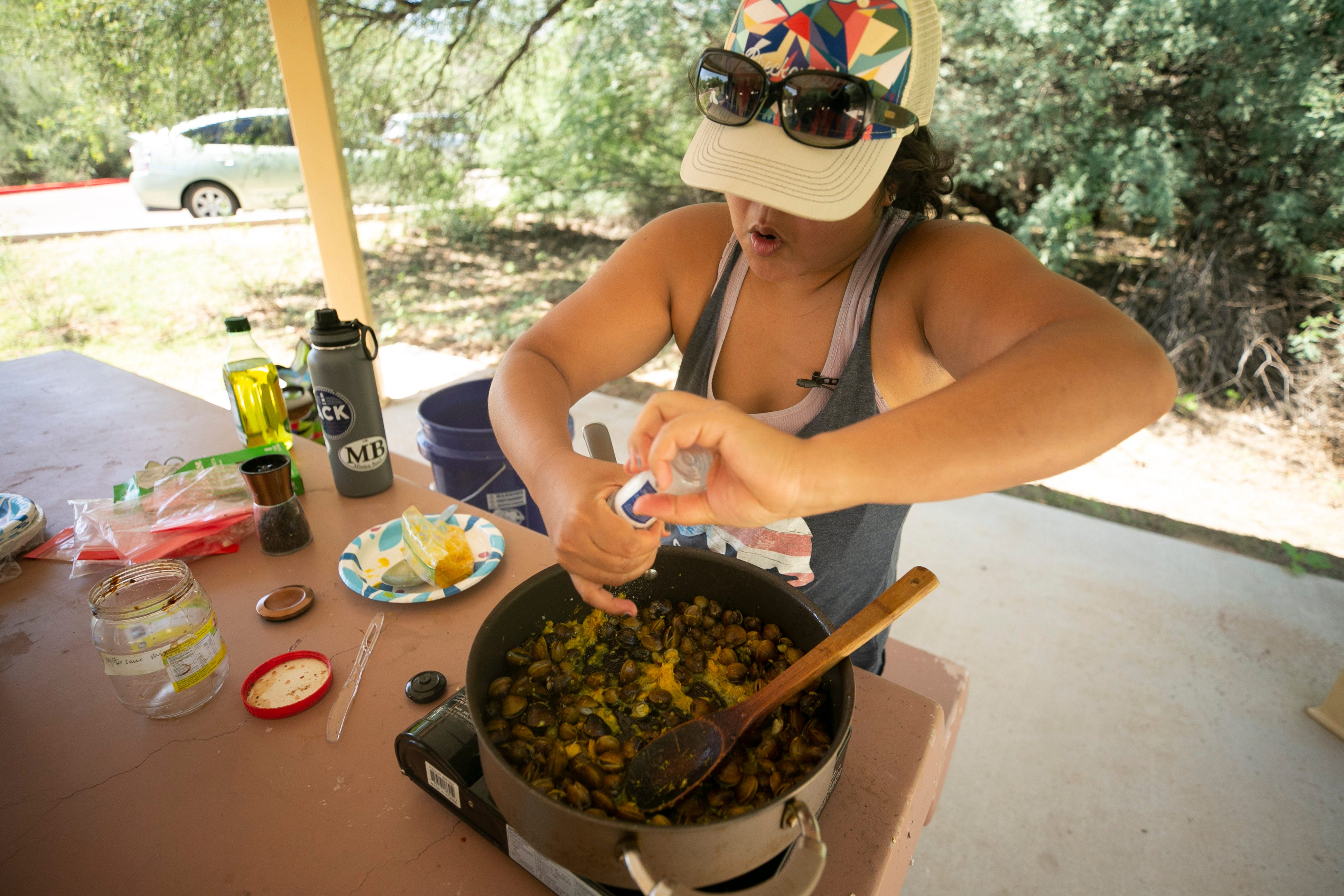 Jenneen Sambour of Phoenix stir-fries Asiatic clams just taken from the Verde River with Kroeung, a Cambodian marinade and spice paste at the Needle Rock Recreation Site outside of Rio Verde on July 28, 2021.