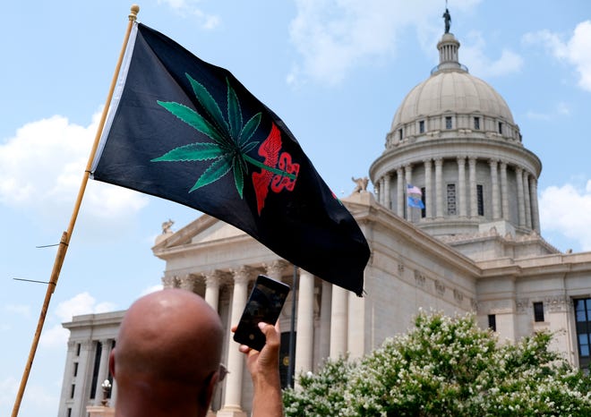 A man takes a photo of a medical marijuana flag July 30 in front of the Capitol as supporters of medical marijuana rally at the Capitol in support of better transparency from the Oklahoma Medical Marijuana Authority.