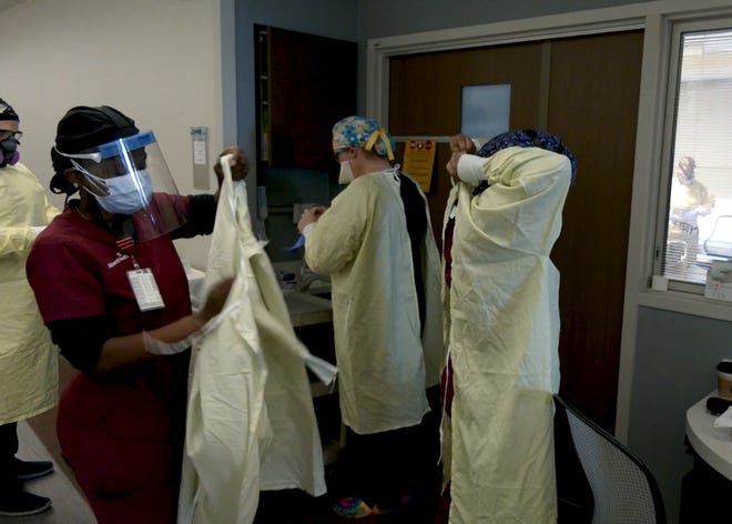 An AdventHealth care team dons protective gear before entering a patient's room in July. The hospital system went to "black" status after an astronomical surge in COVID admissions.