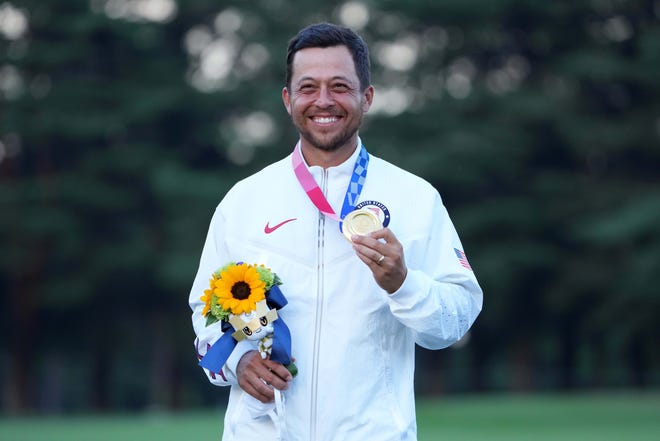 Xander Schauffele celebrates with his gold medal after winning the men's golf competition.