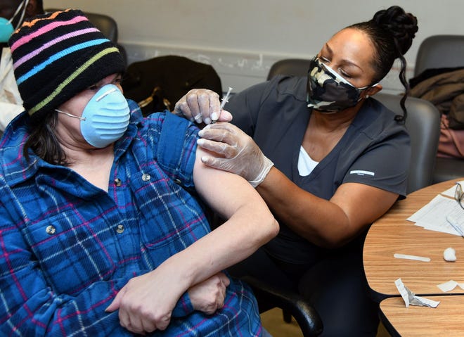 Martha Leipold, left, who receives at-home support from The Arc Baltimore, gets a vaccine shot from nurse Patricia Reese, right, during a January vaccine distribution event at The Arc headquarters. (Barbara Haddock Taylor/Baltimore Sun/TNS)