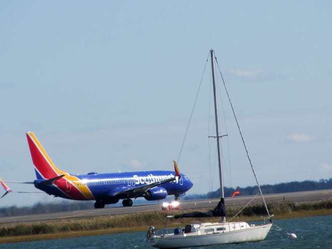 This airplane is waiting for takeoff and the boat is waiting to sail in East Boston.