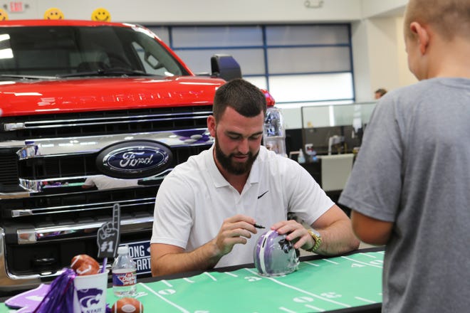 Kansas State quarterback Skylar Thompson signs a souvenir helmet for a young fan Wednesday during an appearance at Long McArthur Ford in Salina.