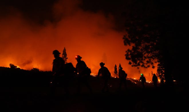 Inmate firefighters walk along the Dixie Fire burn area west of Chester on Wednesday night, Aug. 4, 2021.