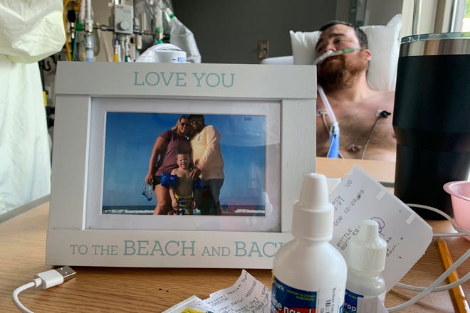 A framed photo of his family sits in front of a COVID-19 patient in an intensive care unit in Osage Beach, Mo., on July 26, 2021.