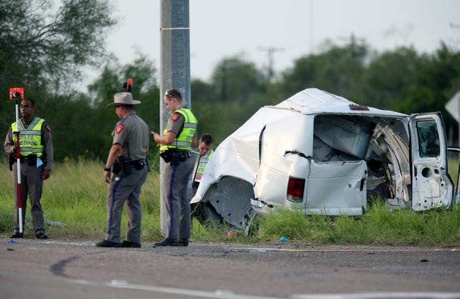 Texas Department of Public Safety officers stand near a vehicle where multiple people died on Wednesday after the van carrying migrants tipped over just south of the Brooks County community in Encino, Texas.