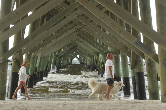 People walk along the beach at Oak Island. Without lifeguards along Brunswick County beaches, some are considering drones to help with safety concerns.