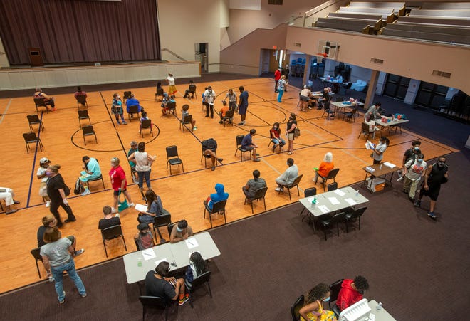 People wait to get their COVID-19 vaccine Saturday at the "Back-to-School Vax and Dash" at the Brownsville Community Center in Pensacola. The first 200 people to receive a vaccine Saturday received a $25 Walmart gift card, as well as a backpack filled with school supplies.