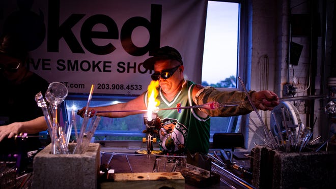 Glass artist Brandon Hall works on a piece in studio at Stoked smoke shop and glass gallery in Bridgeport, Connecticut.
