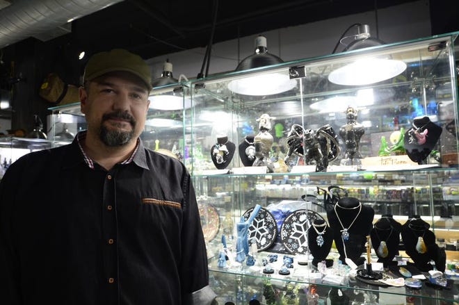 Tito Bern, co-founder of The Bern Gallery in Burlington, Vermont, poses with cases of glass art, including his own artisan pipe creations on the top shelf.