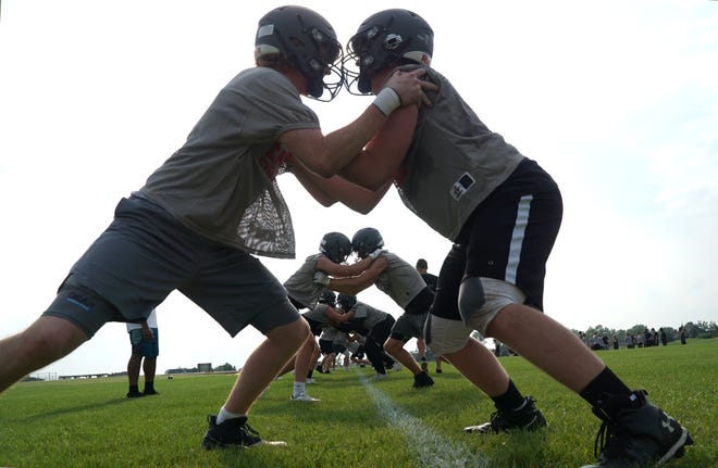                                South Lyon High East varsity football players lock up in a blocking drill during their first day of practice on Aug. 9, 2021.