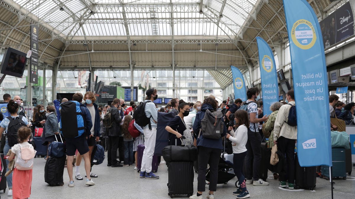 Travelers queue to access trains as railways employees check the COVID-19 health pass that everyone in France needs to enter cafes, trains and other venues, Monday, Aug. 9, 2021, at the Gare de Lyon train station in Paris.