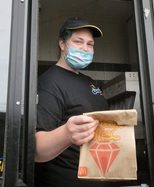 Jane Schultz of McDonald's in Wooster wears her mask as she hands out orders to customers.