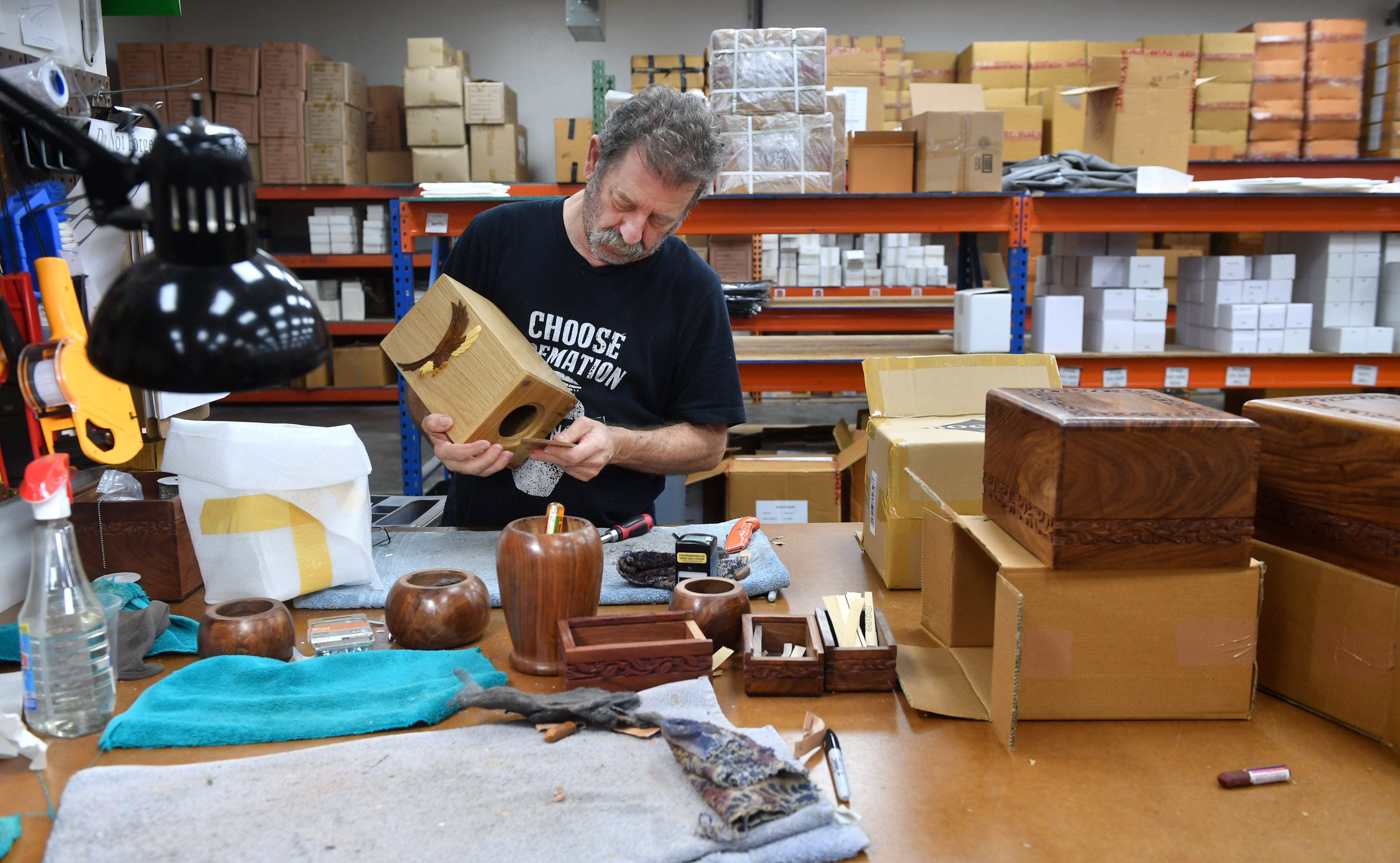 Charlie Miller, warehouse assistant, performs a quality control check on an urn before shipping it to a customer.
